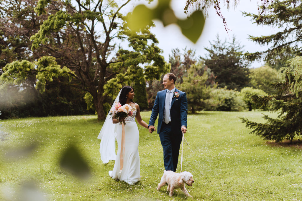 bride and groom walking their dog in the arboretum