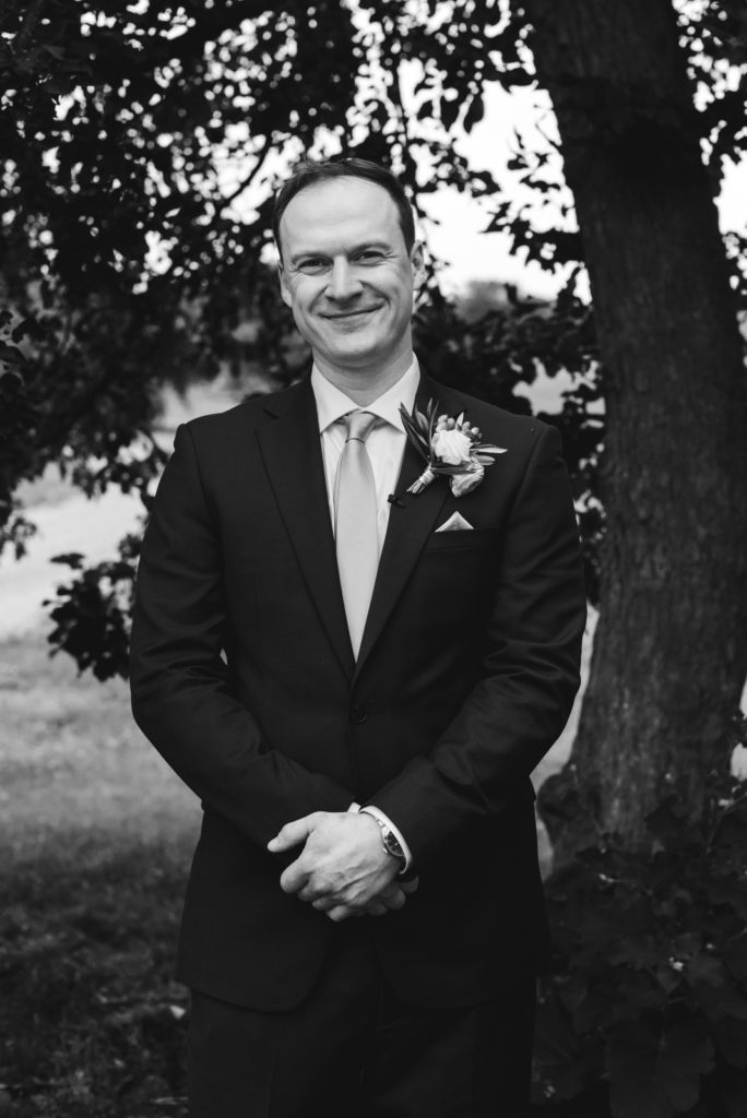 groom smiling at the camera in black and white