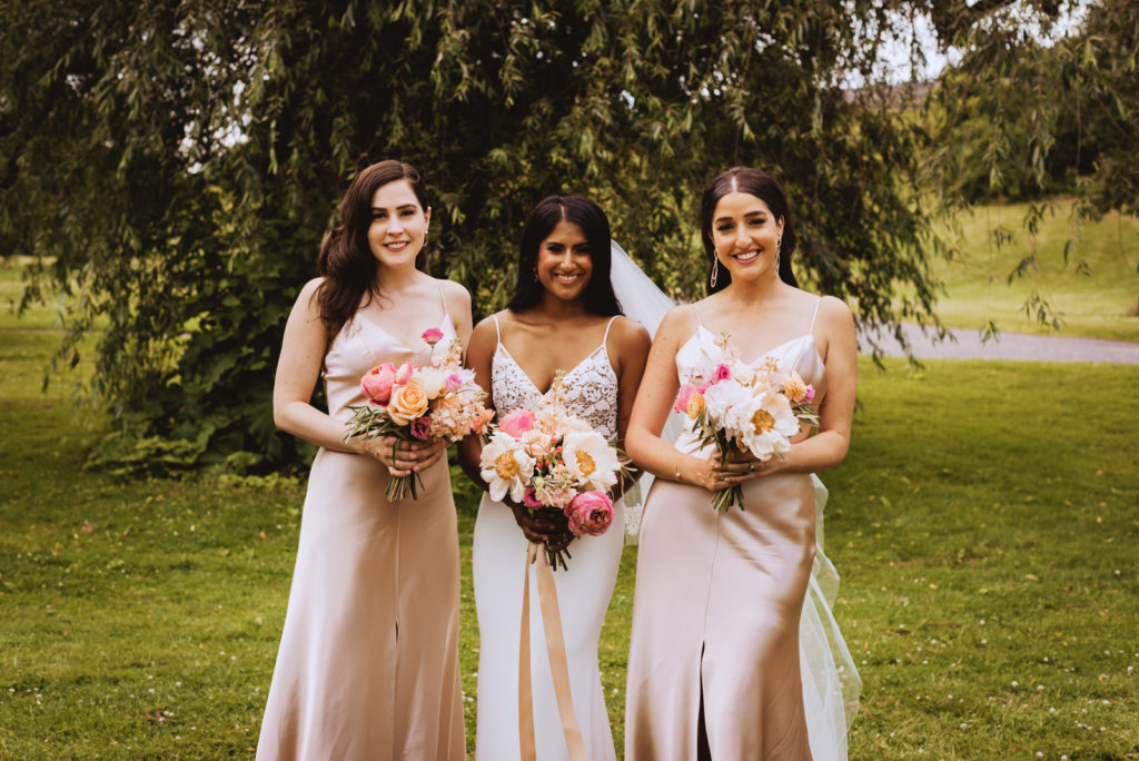 bride and bridesmaids in rose gold underneath willow tree