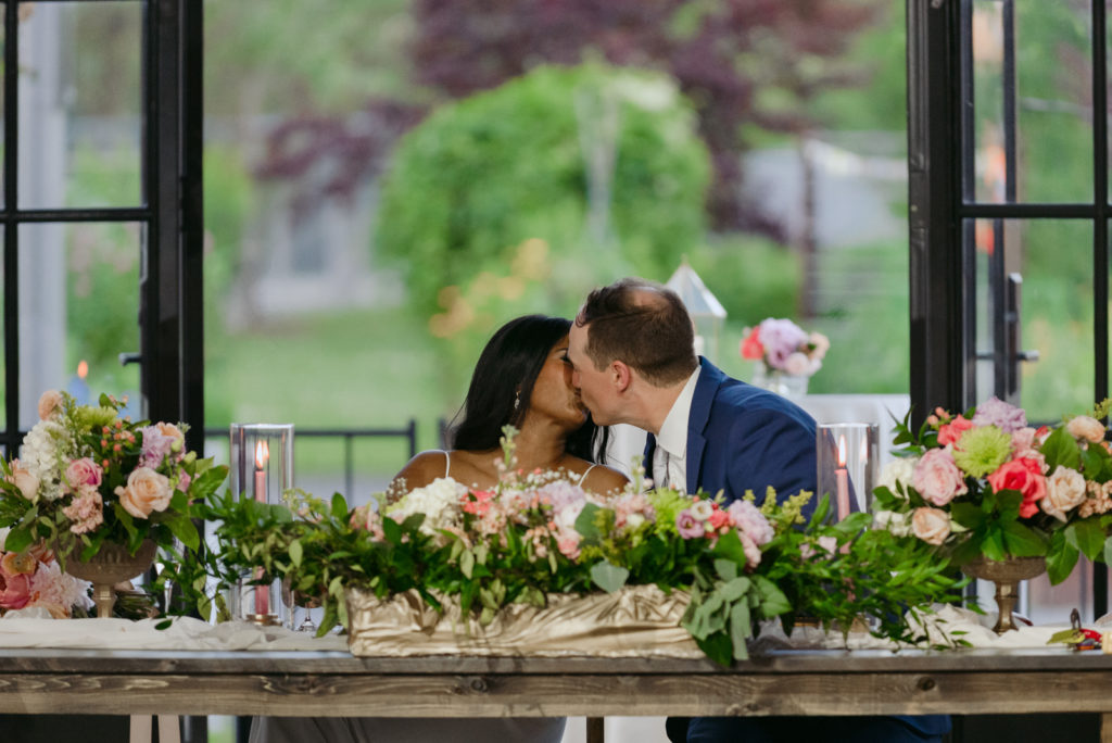bride and groom kiss at head table