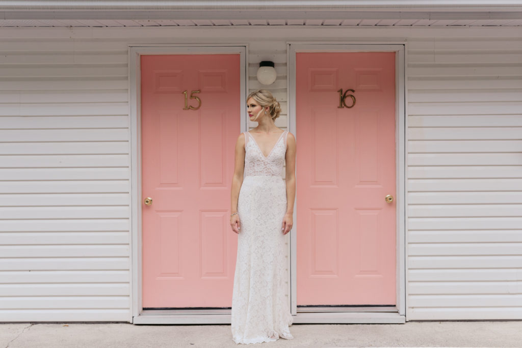 bride standing outside pink motel doors at the June Motel