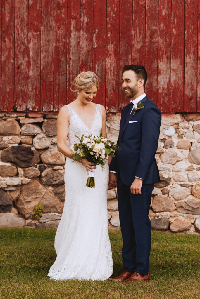 bride and groom in front of red barn at Fields on West Lake