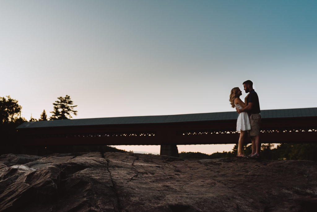 engaged couple by the wakefield covered bridge at sunset