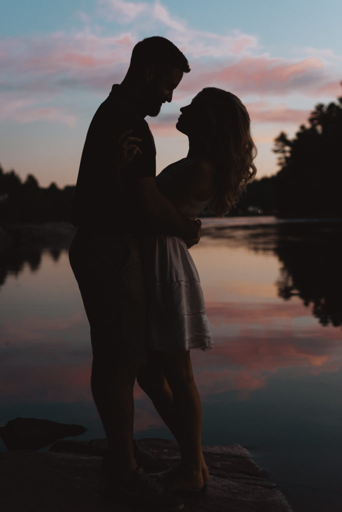 silhouette of engaged couple by the water with sunset sky