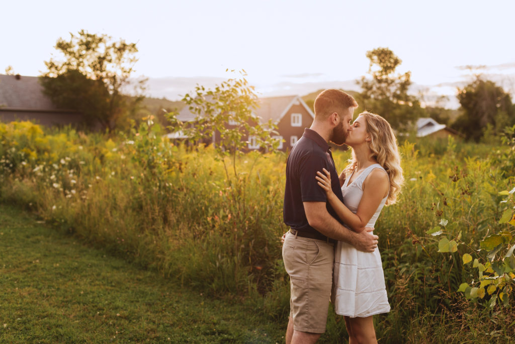 engaged couple kissing at sunset in the country