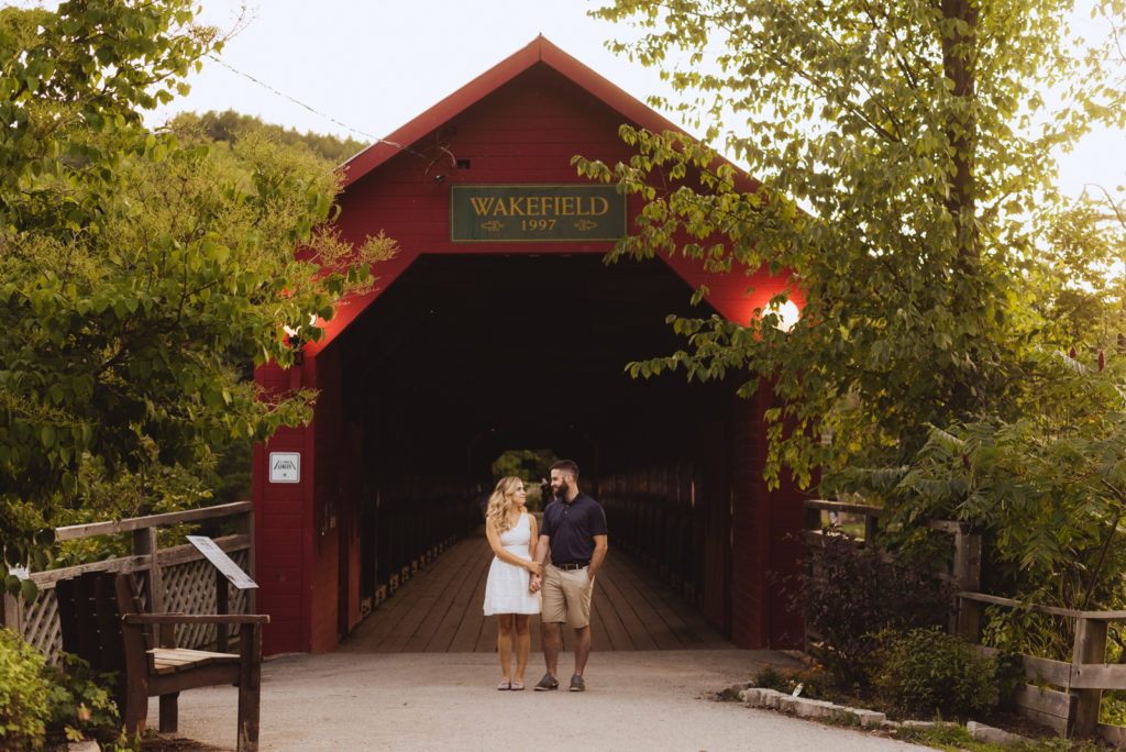 engaged couple standing underneath wakefield covered bridge