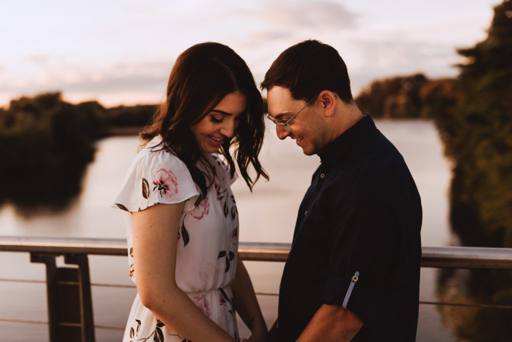 Engaged couple smiling and laughing together a ton sunset