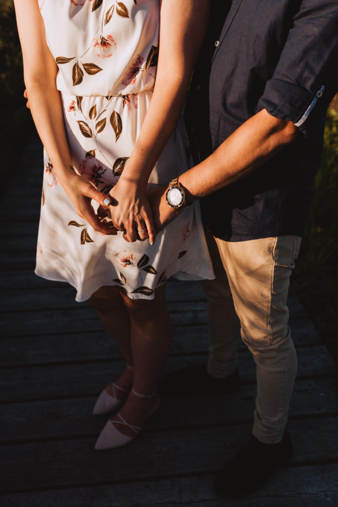 engaged couple's hands interlaced together at sunset