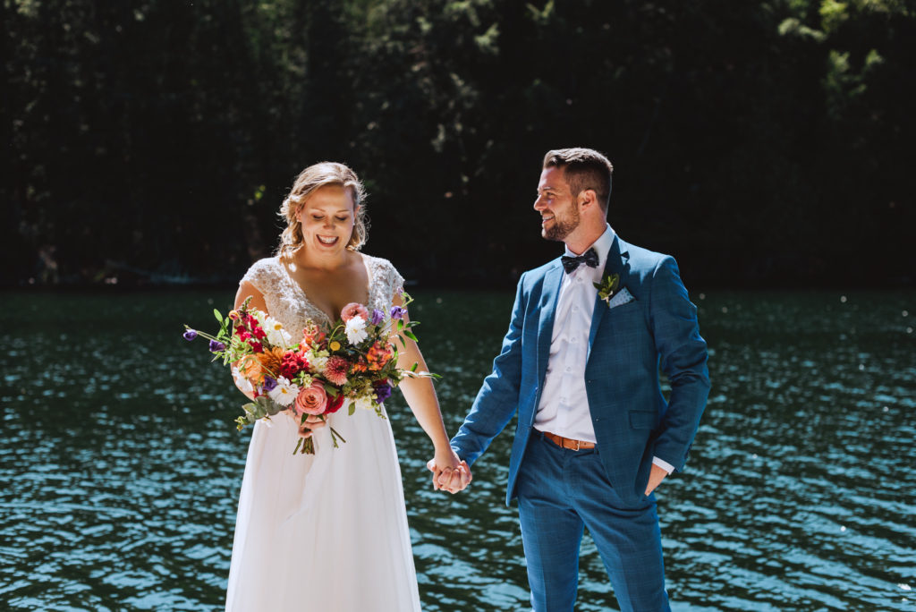 bride and groom by the water holding wedding bouquet