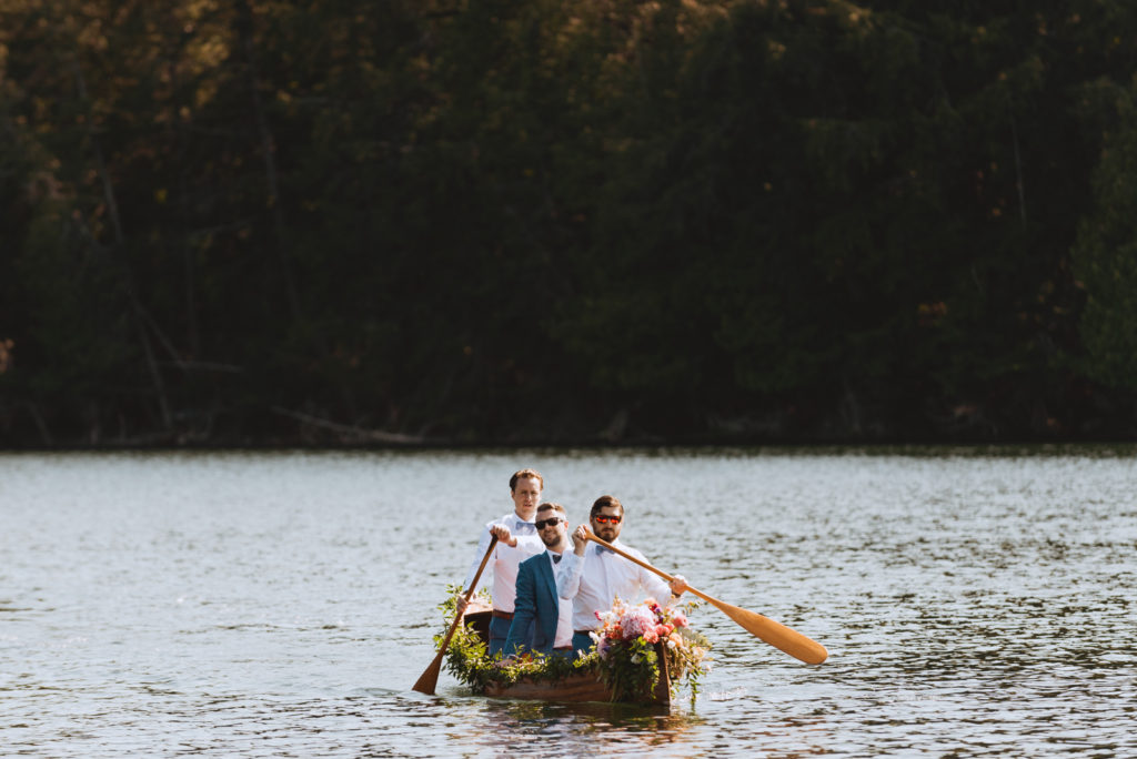 groom and groomsmen canoeing to wedding ceremony