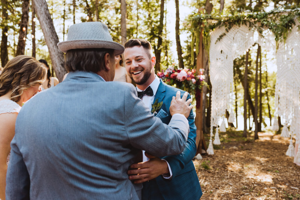 groom hugging father of the bride as he gives his daughter away