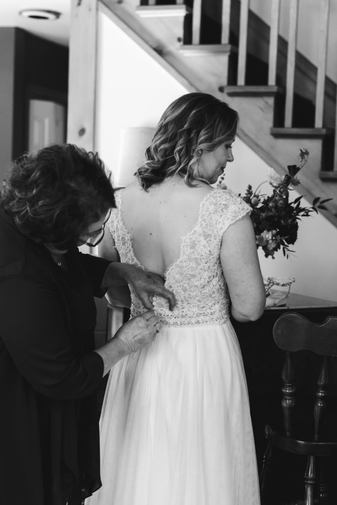 bride's mother tying up the bride's dress