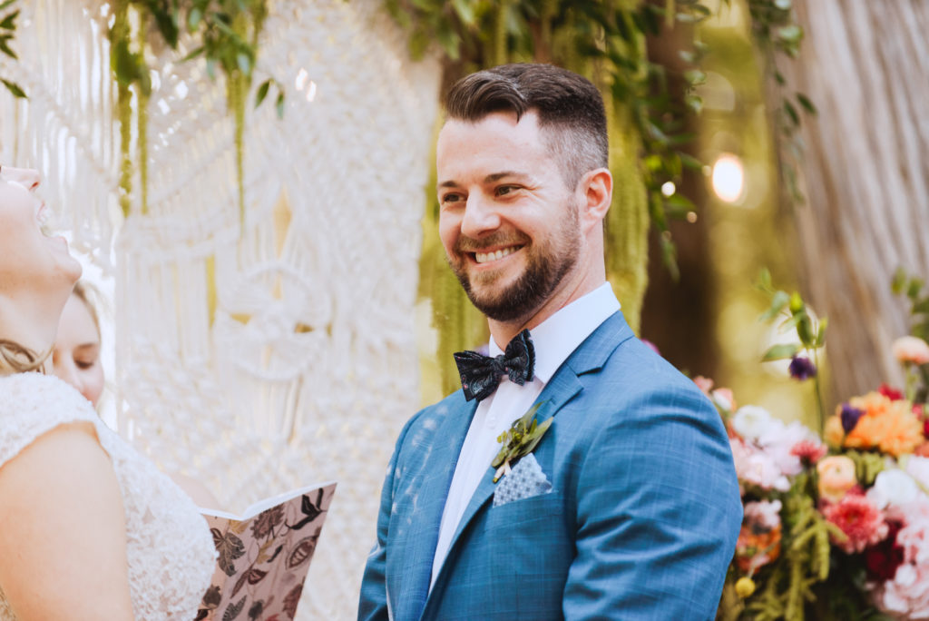 groom smiling during outdoor wedding ceremony at cottage