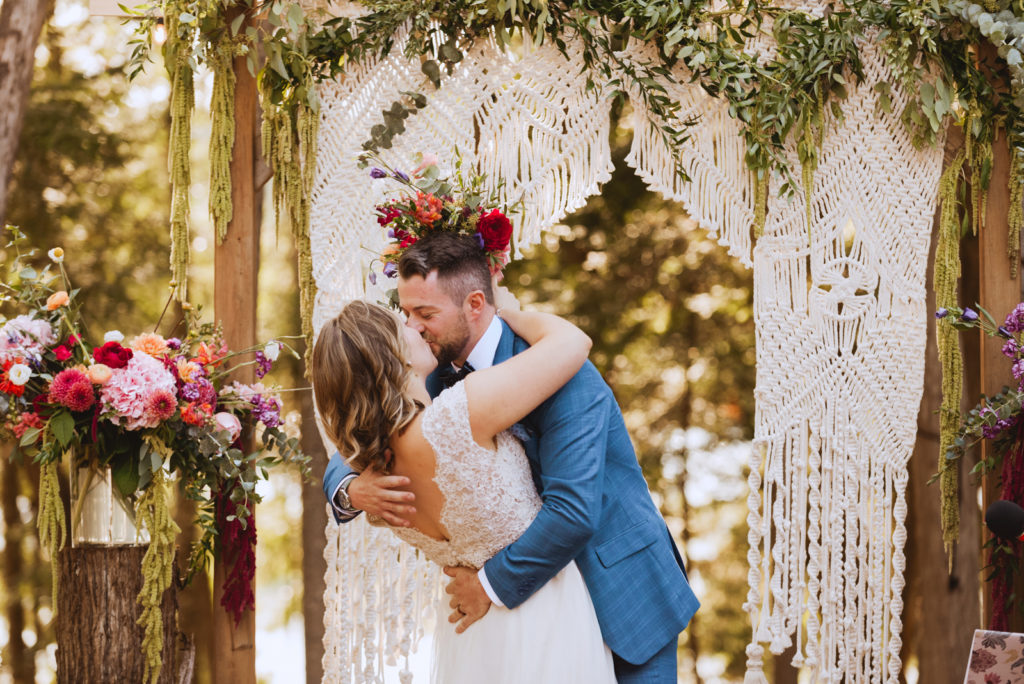 first kiss under macrame arch at cottage wedding