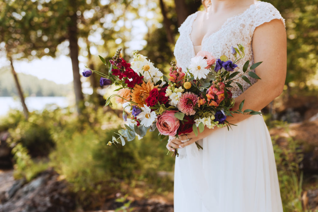 bride holding bouquet by the lake