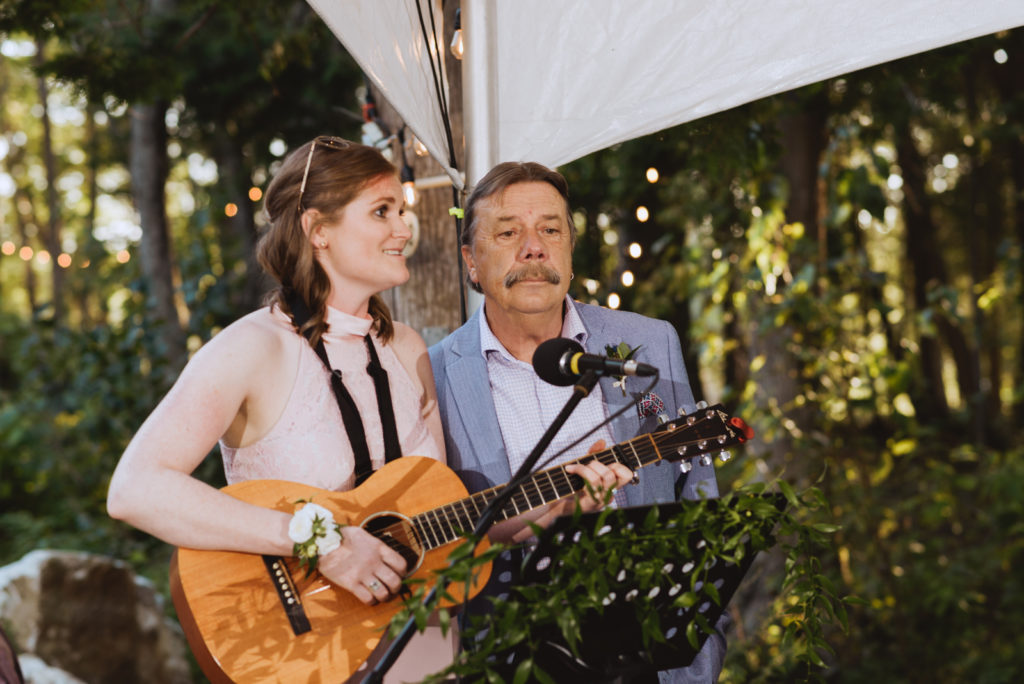 bridesmaid and father singing a song on the guitar at wedding