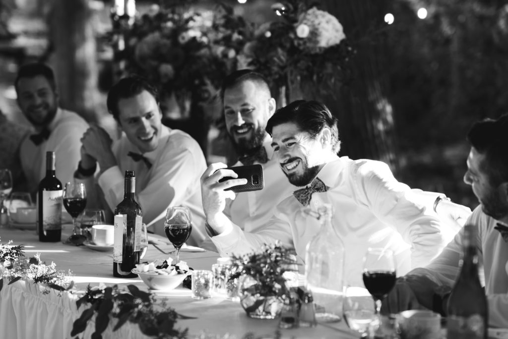 groomsmen taking selfies at wedding reception table
