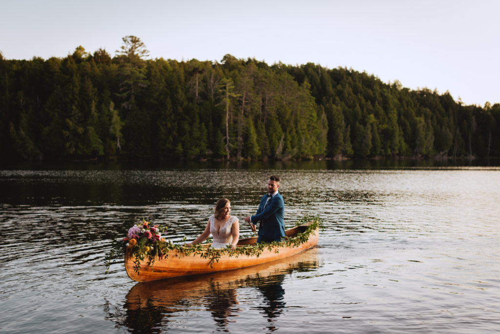 bride and groom canoeing on a lake at sunset