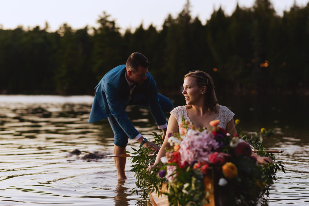 bride and groom getting into floral canoe at sunset