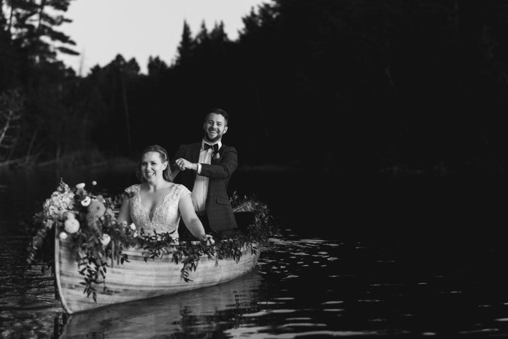 bride and groom canoeing with floral canoe at sunset