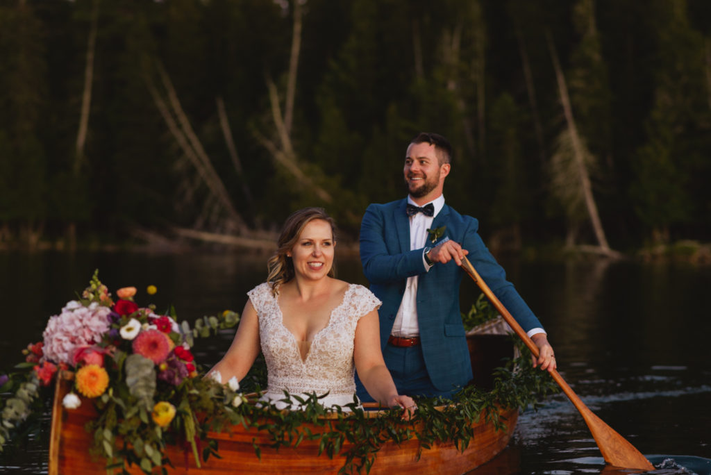 bride and groom canoeing with floral canoe at sunset