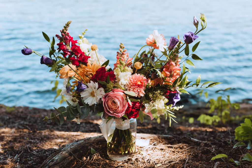 bright floral bouquet in a vase by the water