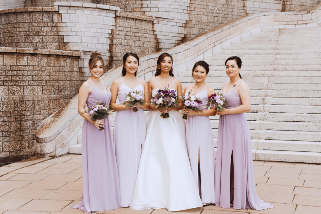 bride and bridesmaids in front of stone steps