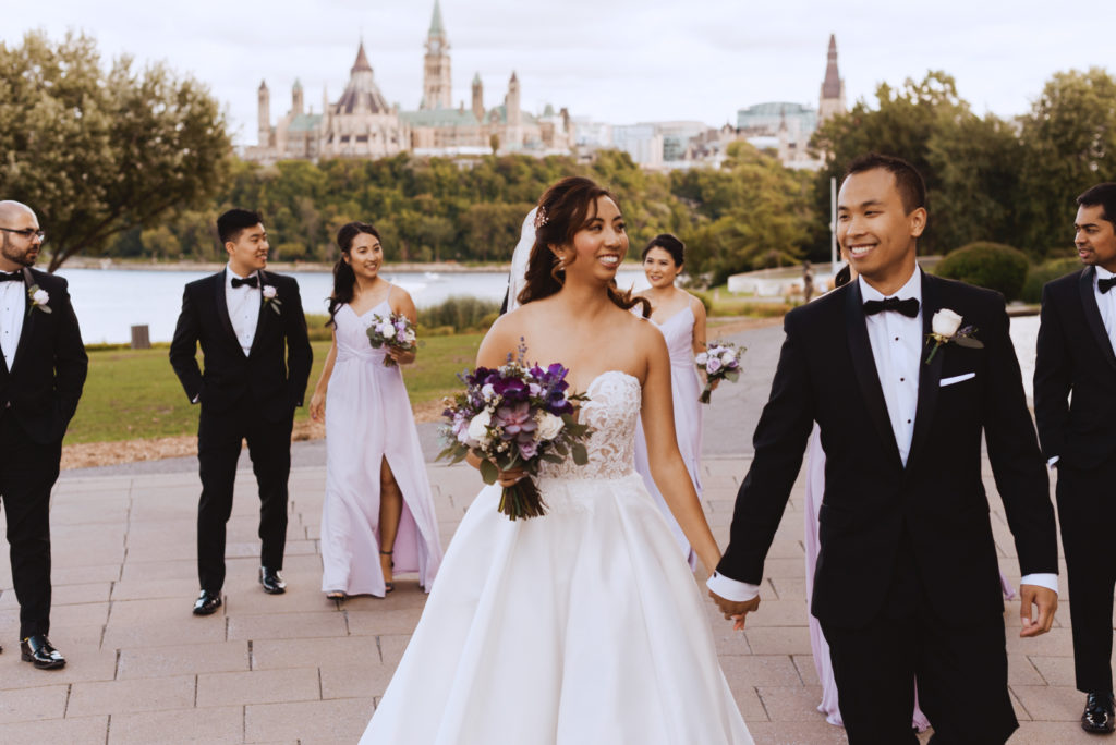 candid photo of wedding party walking around in front of parliament buildings