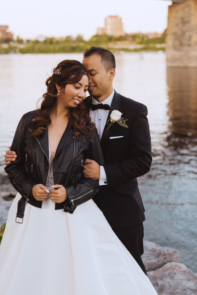 bride wearing the just married leather jacket by the water at sunset