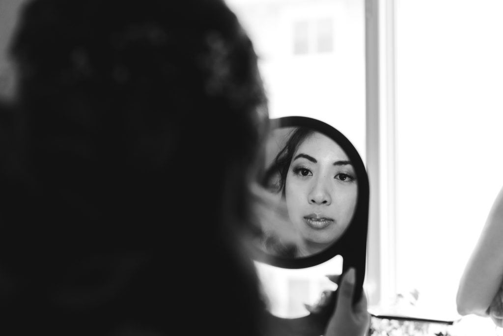 bride looking at her makeup in the mirror
