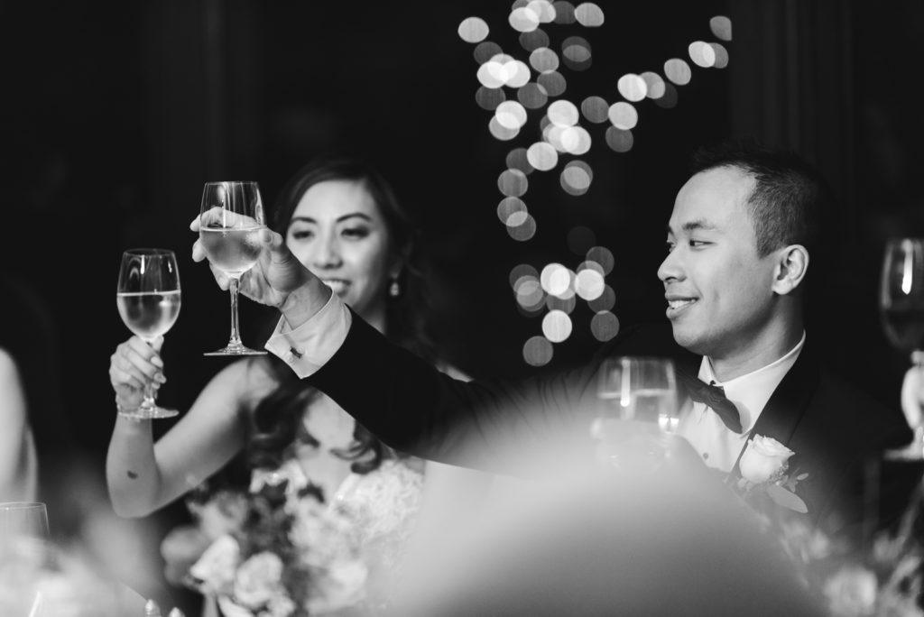 bride and groom toasting in black and white