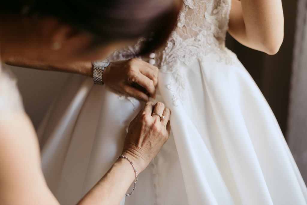 bride's mother tying up the bride's dress