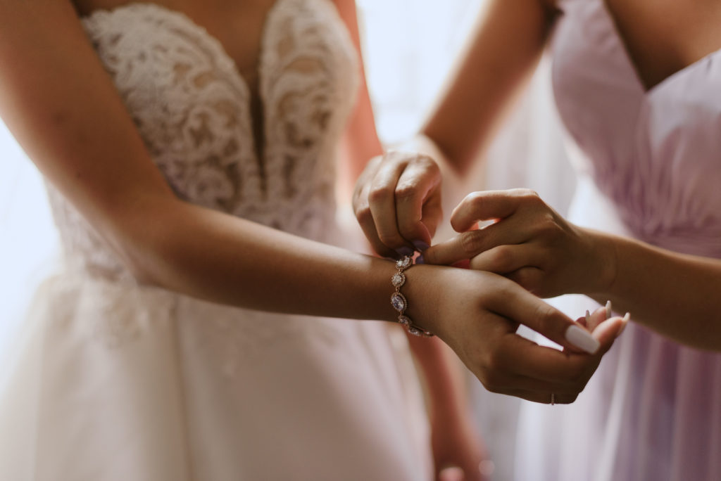 bride's sister putting on the bride's bracelet