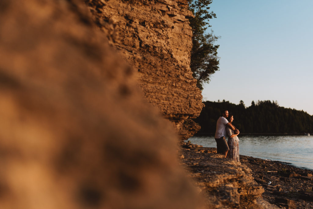 engaged couple looking out at the water at sunset