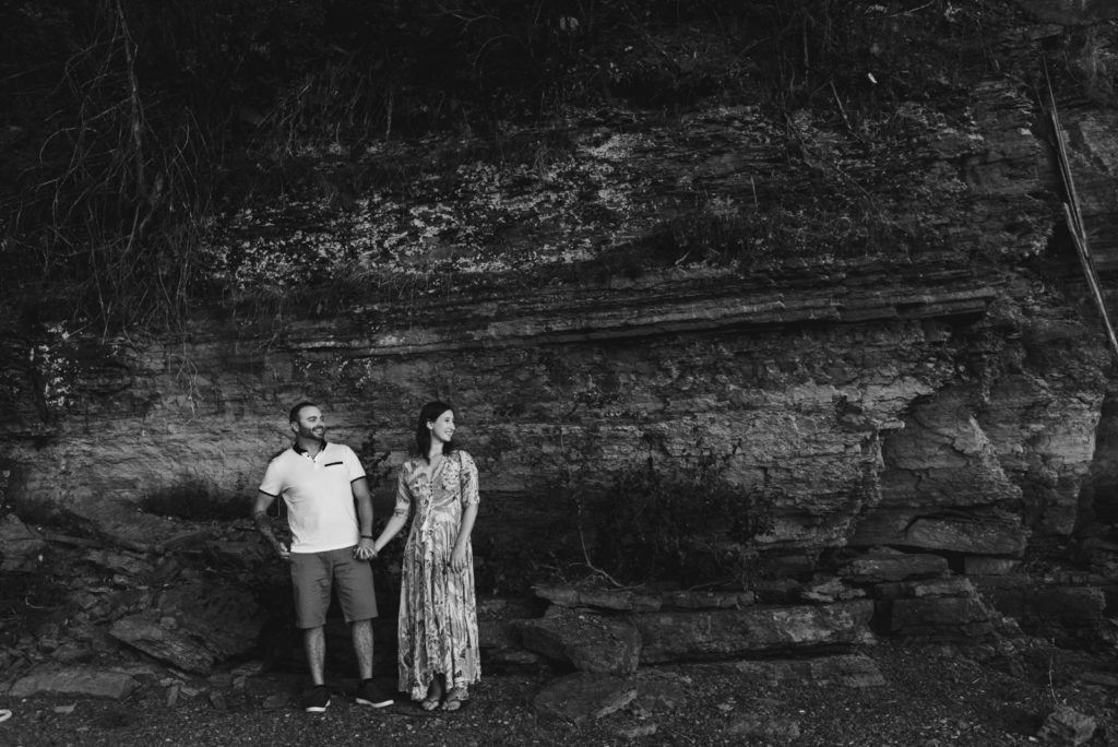 engaged couple by rock face in black and white