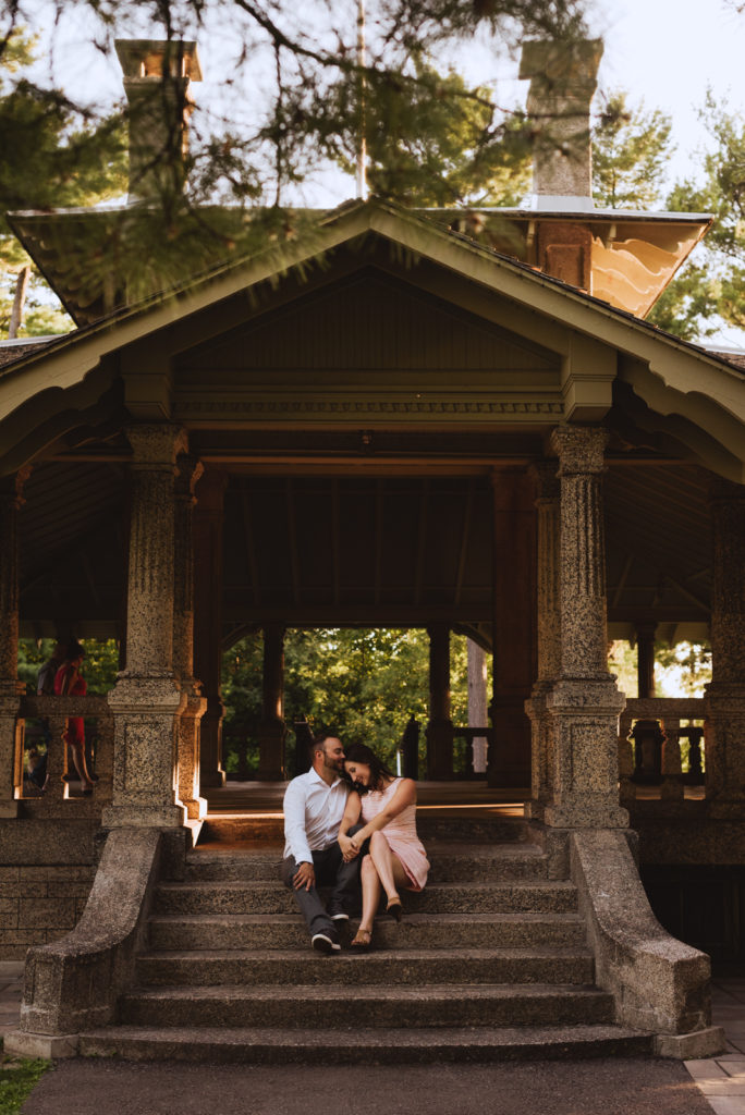 engaged couple sitting on steps of rockcliffe park pavilion