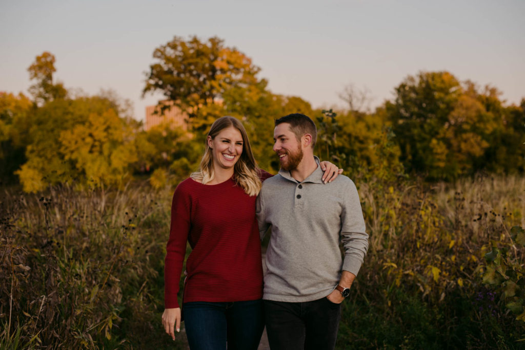 engaged couple laughing at sunset in a field