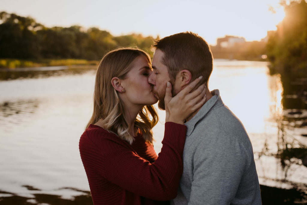 engaged couple kissing at sunset by the water