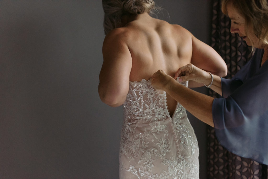 mom helping bride into her dress