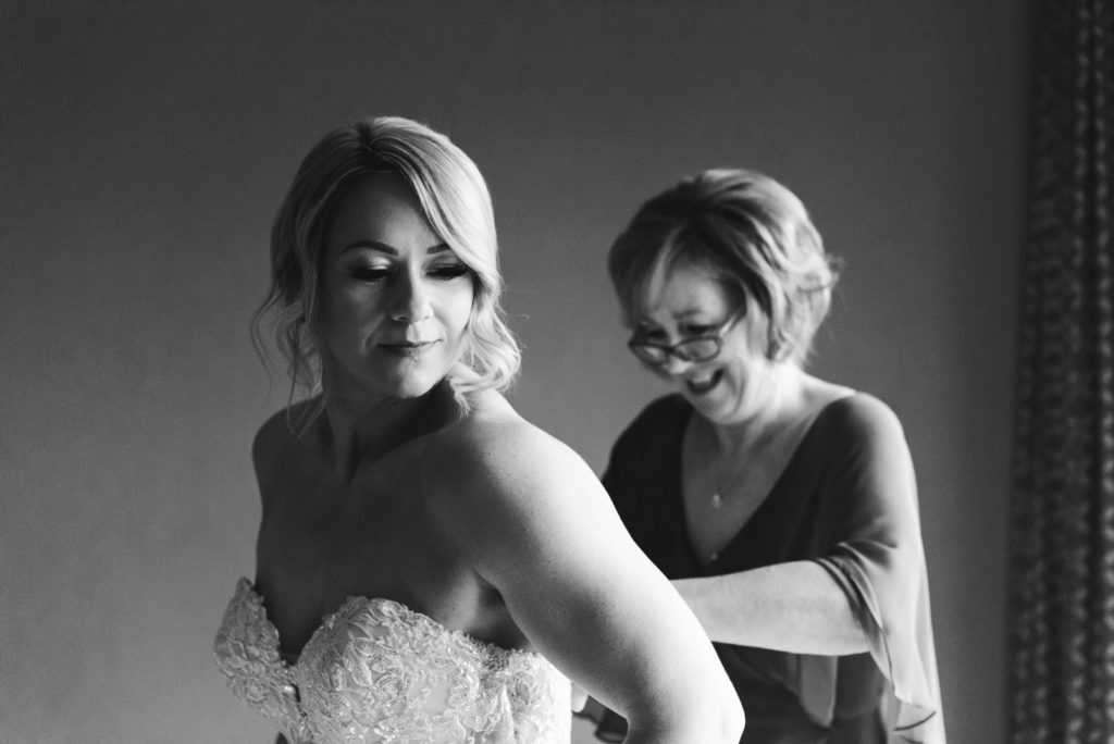 mother of the bride helping bride into her dress