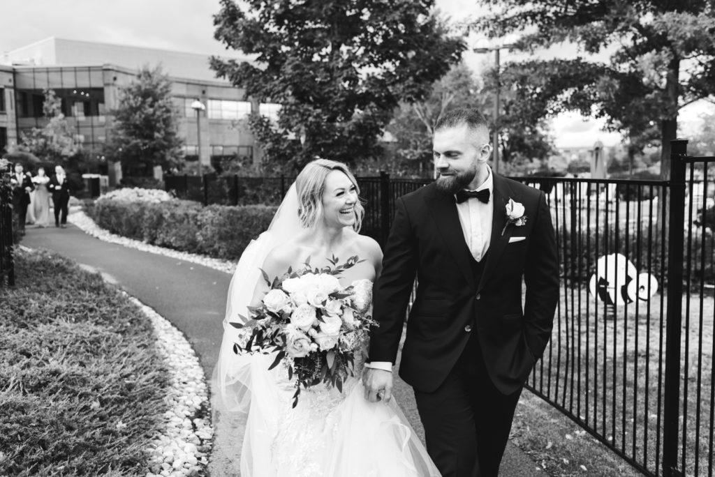 bride and groom walking down path at the brookstreet hotel smiling