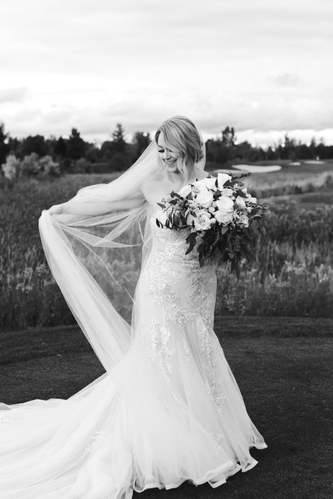 bride playing with her veil in a field