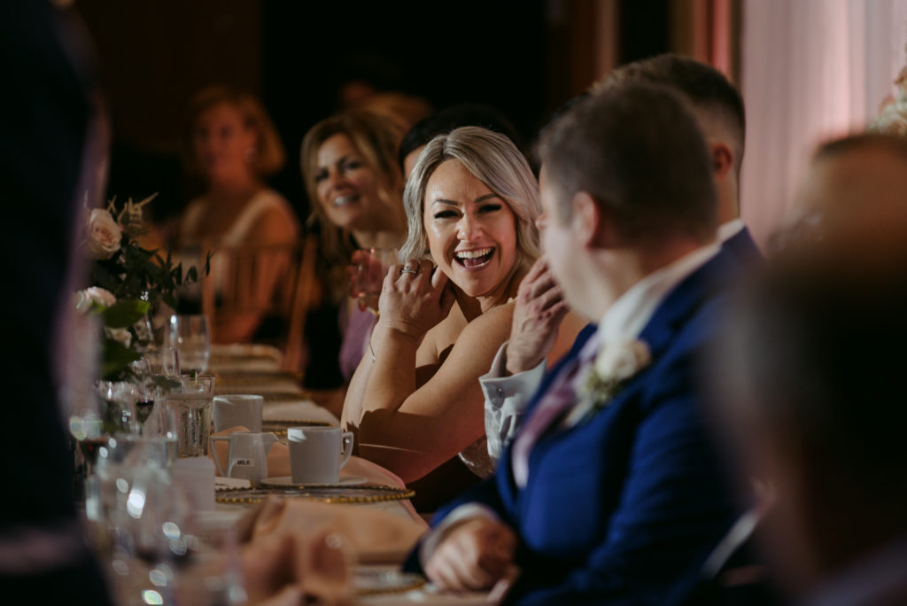 bride laughing at head table during speeches