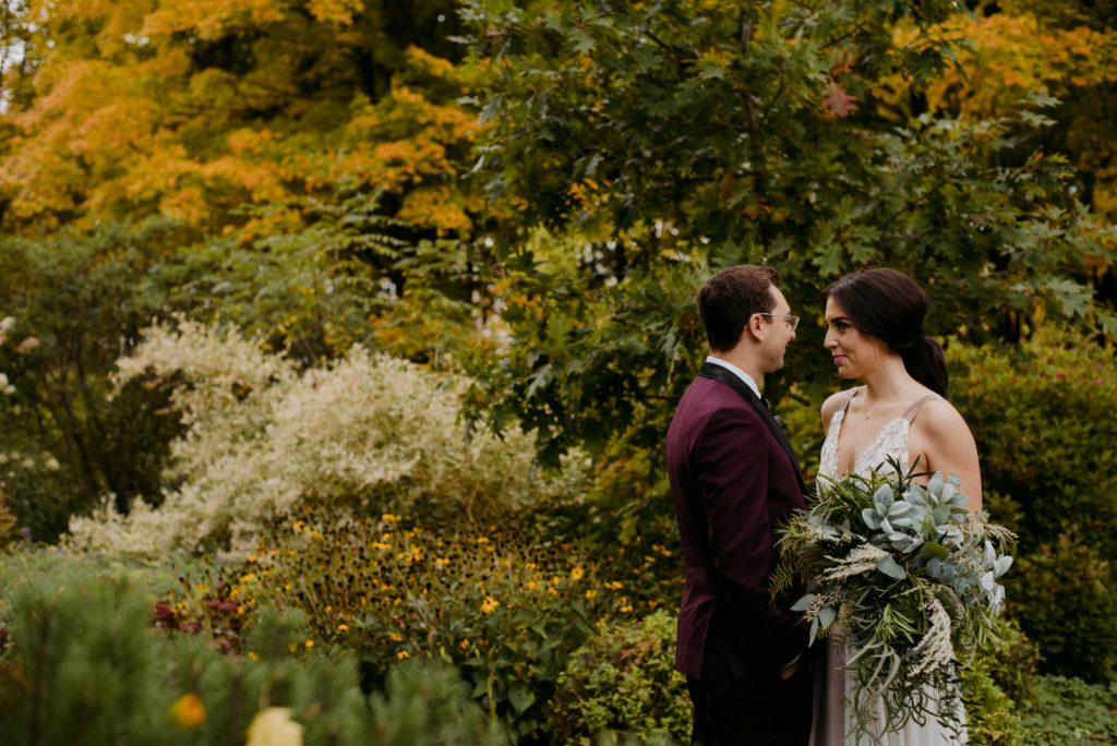bride and groom among the trees during fall wedding