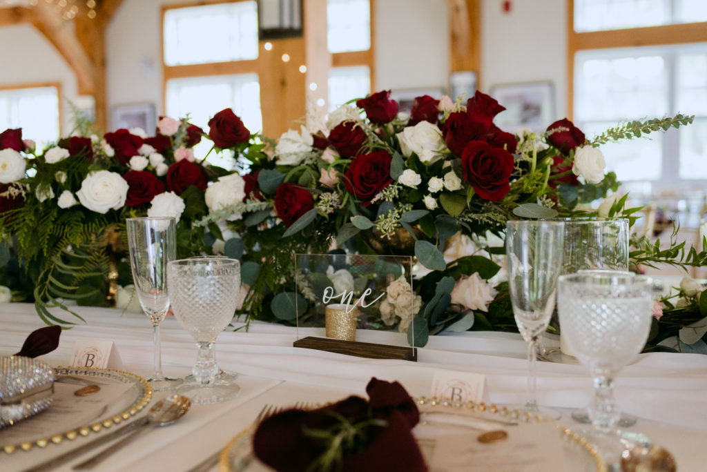 gold and marsala table setting at wedding with large floral centrepiece