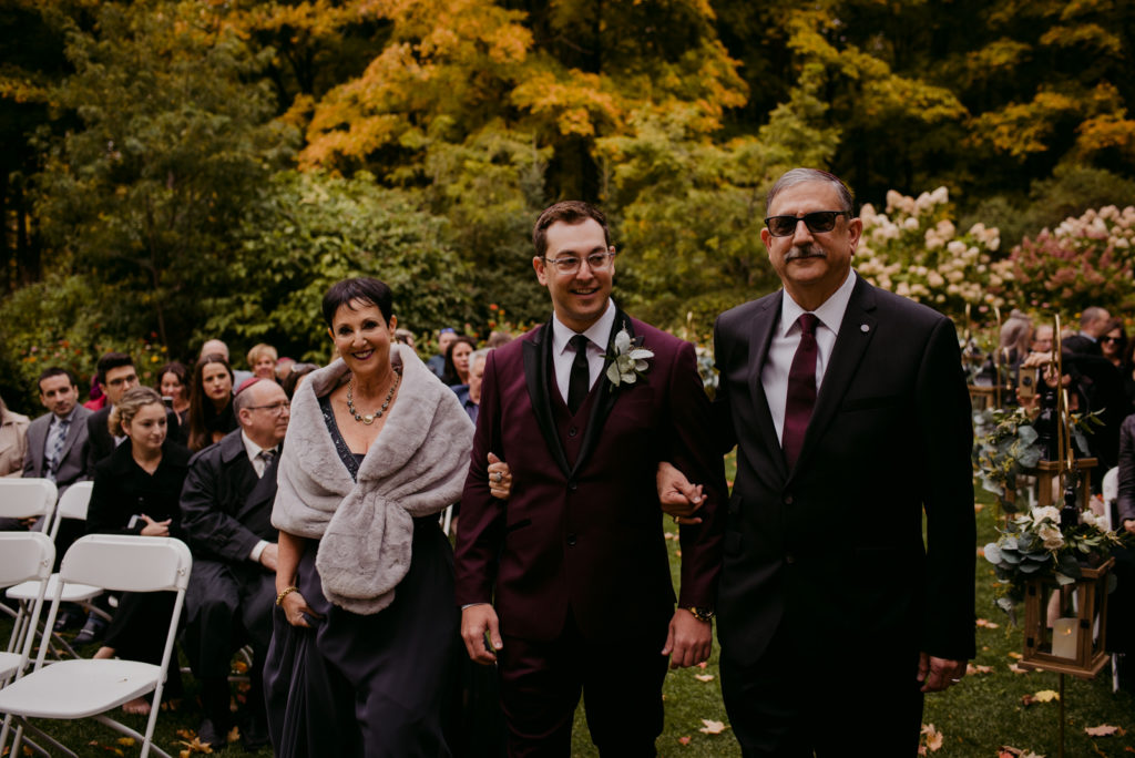groom walking down the aisle with his parents