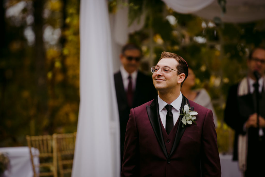 groom smiling as the bride walks down the aisle