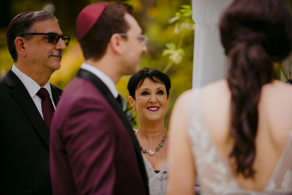 mother of the groom smiling during wedding ceremony under the chuppah