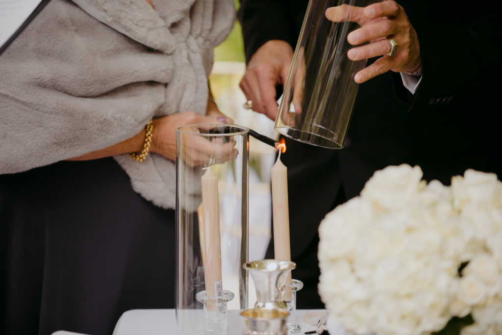 groom's parents lighting candle during jewish ceremony