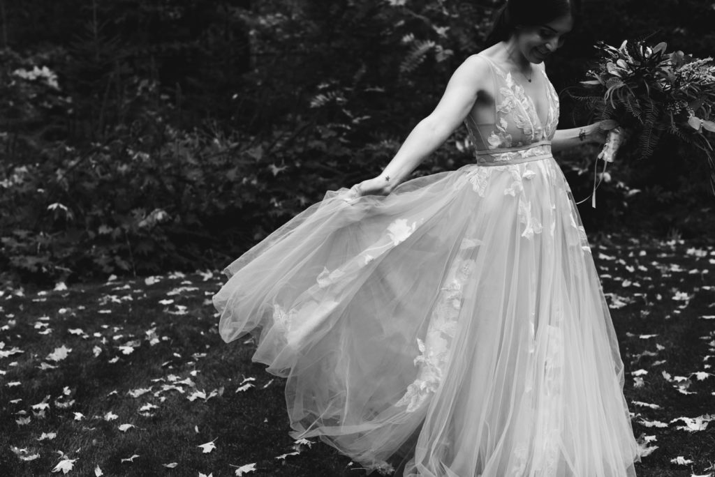 bride playing with her willow by waters dress among fall leaves